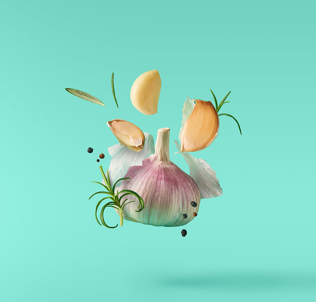 An image of fresh garlic and other herbs suspended in mid-air.