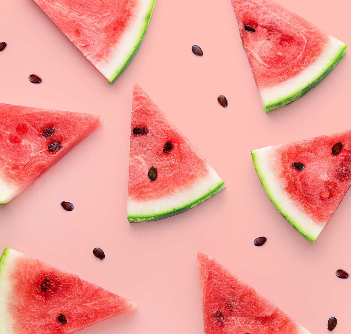 An image of sliced watermelon wedges, scattered with black seeds on a pink background.