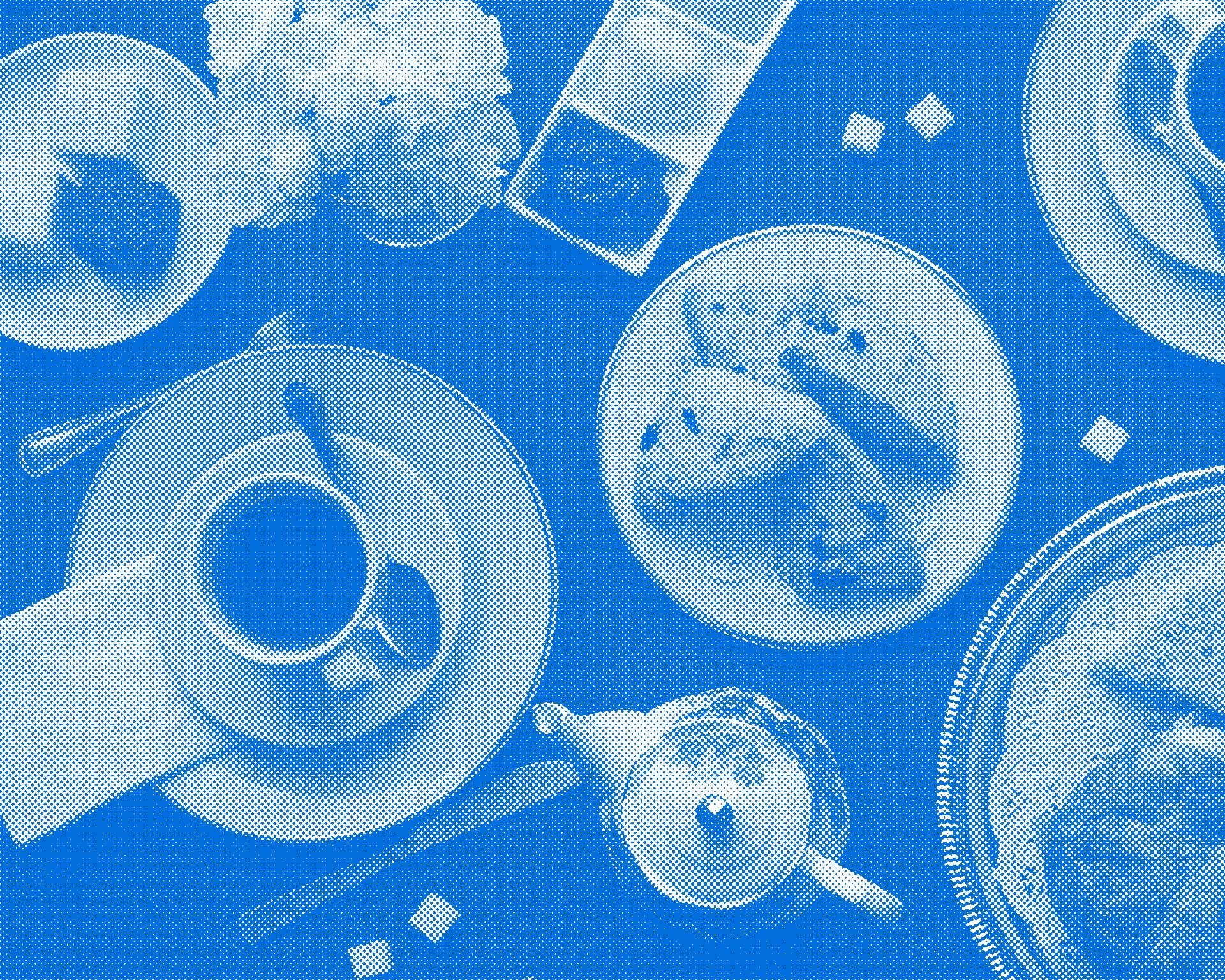 A halftone image of a table top, photographed from directly above, containing teacups, scones,  finger sandwiches, petit fours and scattered sugar cubes.